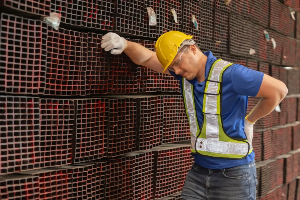 A New Jersey Longshoreman, holding his back displeased with the lumbar pain he is experiencing.