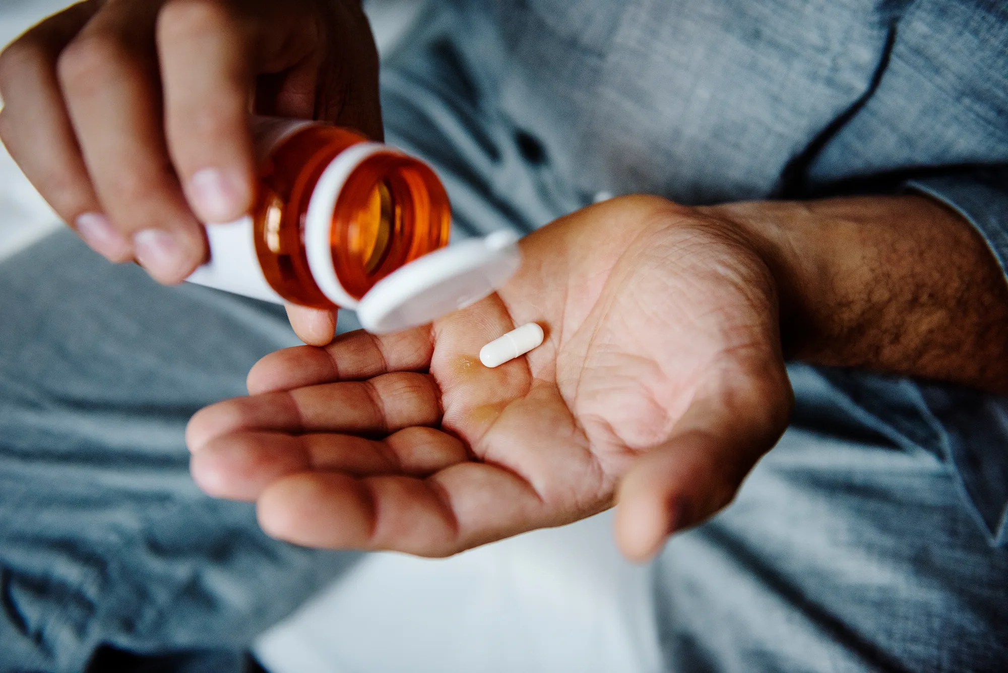 An older man taking medication for spinal pain in New Jersey.