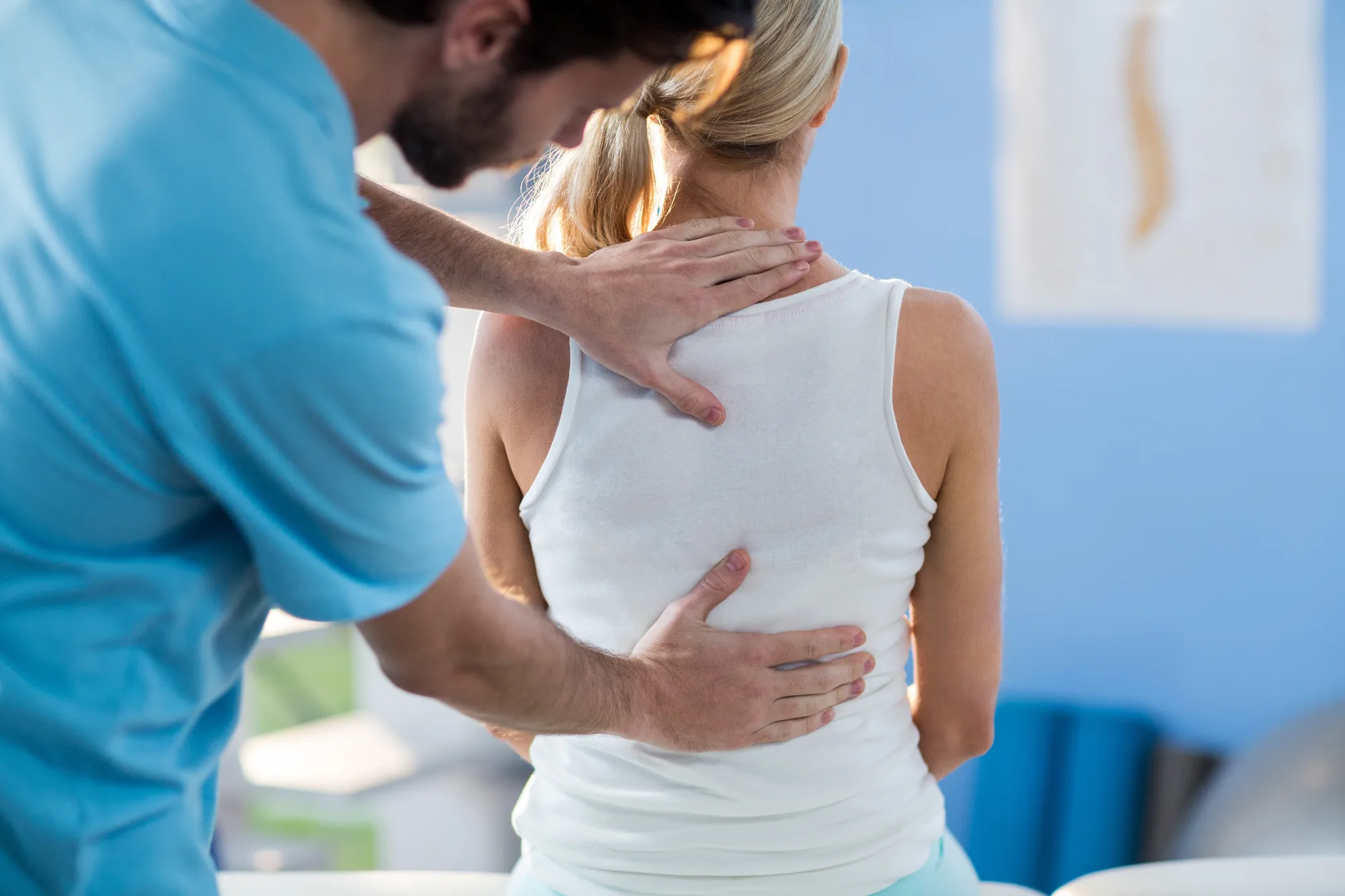 A physical therapist helping a young woman with back pain in New Jersey.
