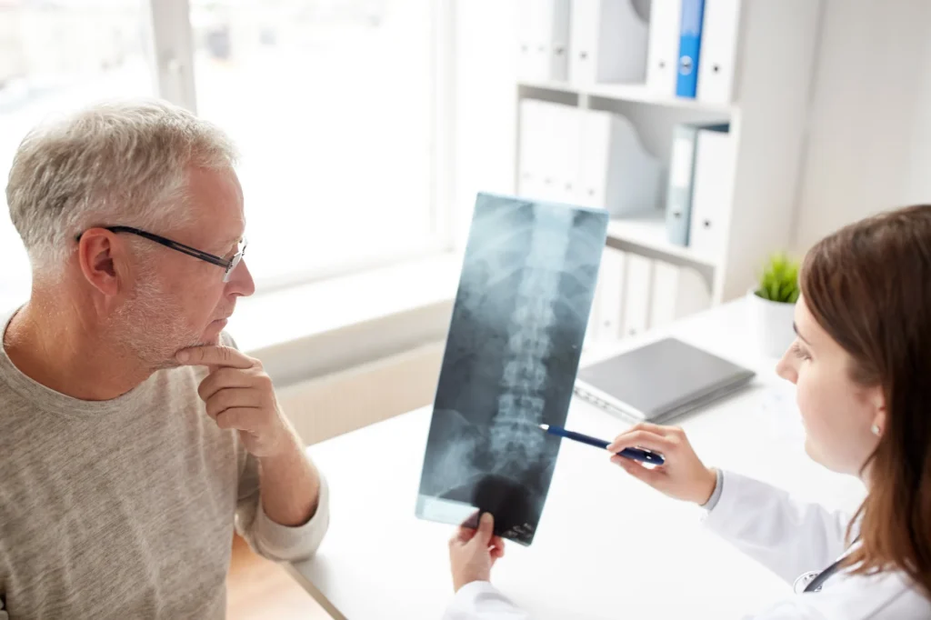 A doctor, showing a patient a spinal x-ray, and explaining how they will relieve their pain.
