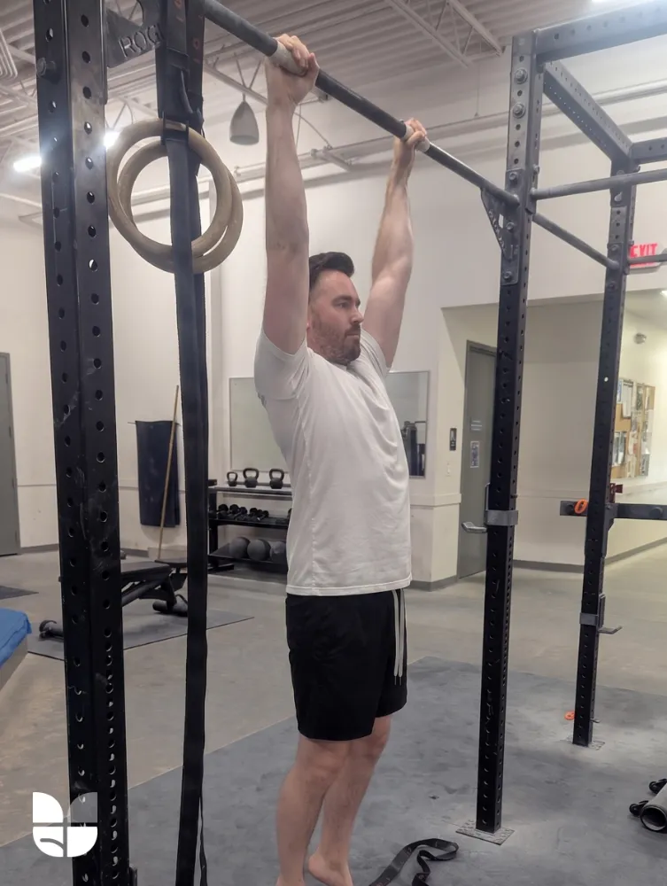A man doing a dead-hang to decompress his spine and relieve pain.