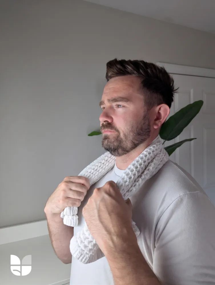 An image of a man holding a towel around his neck in a relaxed position.
