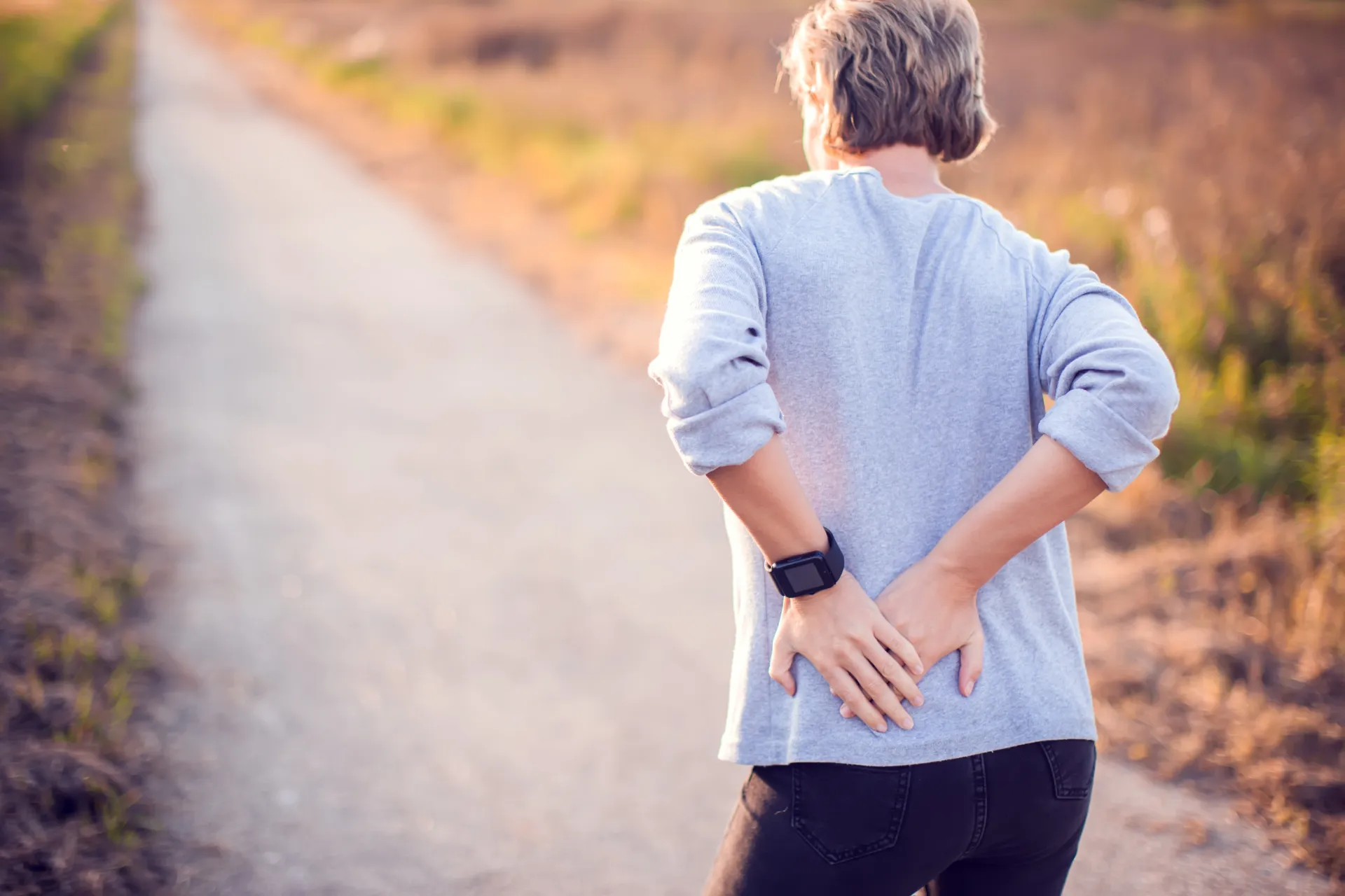 An older New Jersey woman struggling with lower back pain during an afternoon walk.